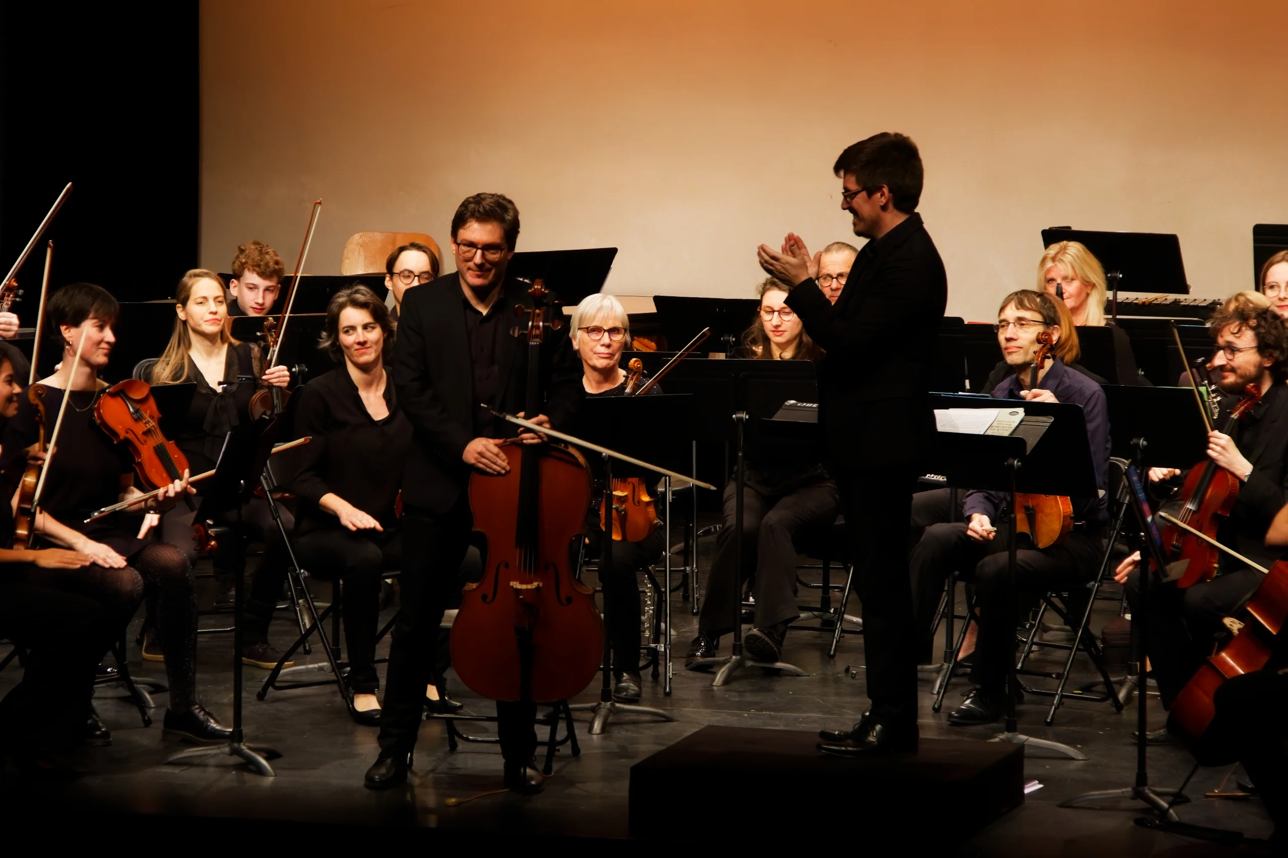 Violoncelliste solo qui salue avec orchestre derrière