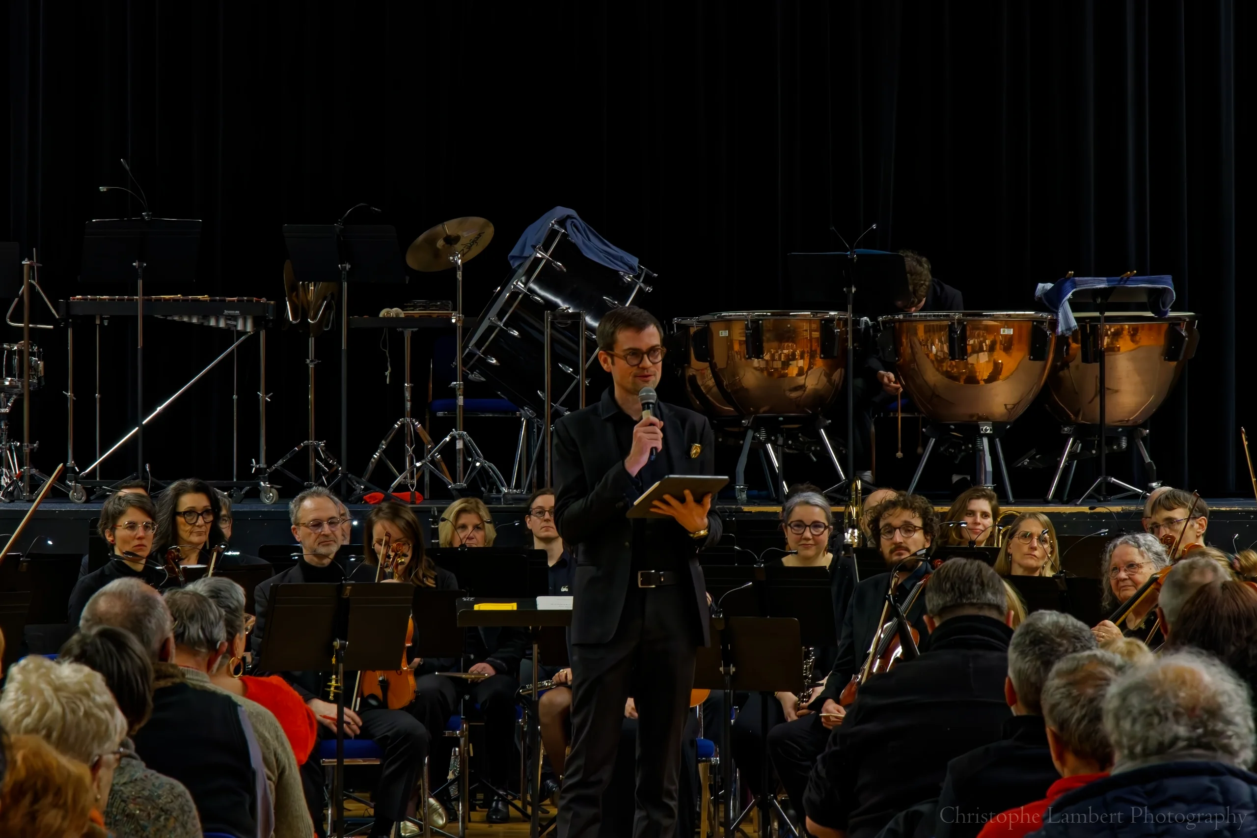 Le Président (Dimitri) devant l'orchestre, faisant le discours d'introduction