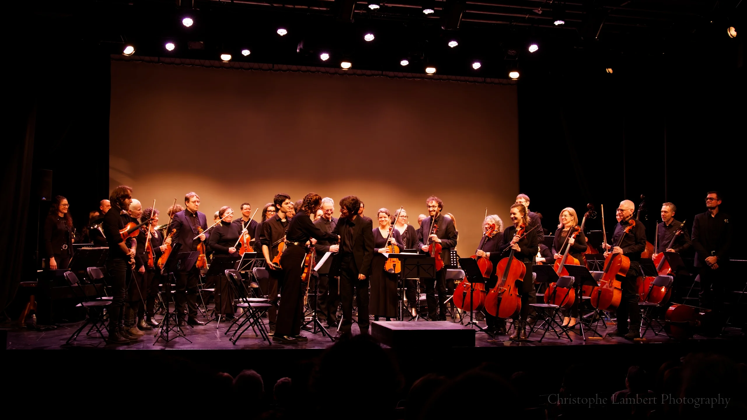 Orchestre est debout, poignée de main entre le chef et la violon solo